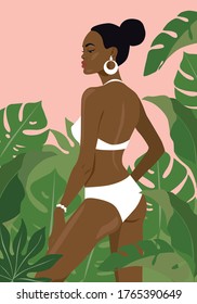 Beautiful black girl in a bikini in the middle of tropical leaves. 