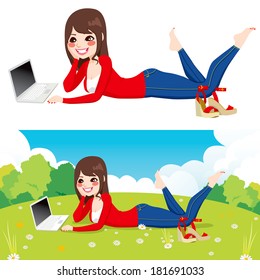 Beautiful brunette woman lying down on grass using laptop on peaceful park with flowers