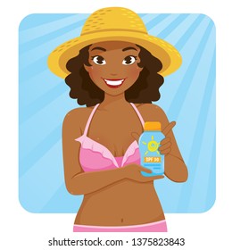 Beautiful dark skinned girl in swimsuit holding a bottle of sunscreen