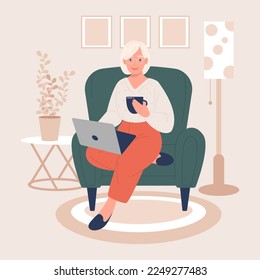 Beautiful elderly woman sitting on an armchair with a laptop and a cup