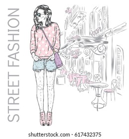 Beautiful girl in shorts, hoodies and boots in heels. Vector illustration for a postcard or a poster. Slender model with long legs against the background of a city street.