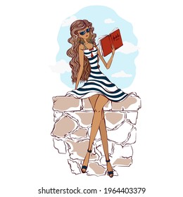 A beautiful girl in a striped light sundress and sunglasses sits on a stone parapet and reads a book. Summer sea vacation. Romantic vacation with a book.