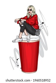 A beautiful girl in stylish clothes sits in a large glass of coffee. Fashion and style, clothing and accessories.