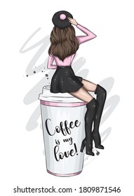 A beautiful girl in stylish clothes is sitting on a large glass of coffee. Food and drinks. Fashion and style, clothing and accessories. Coffee to go. Woman.