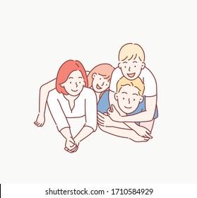 Beautiful and happy smiling young family in white T-shirts are hugging and have a fun time together while lying on the floor and looking on camera. Hand drawn style vector design illustrations.