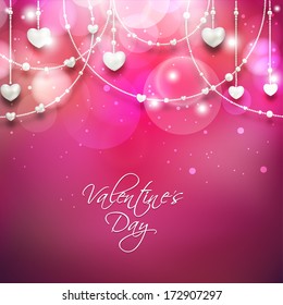 Beautiful Happy Valentines Day concept with hanging heart shapes on shiny pink background. 