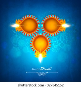 Beautiful illuminated lit lamps on shiny floral design decorated blue background for Indian Festival of Lights, Shubh Diwali (Happy Diwali) celebration. 