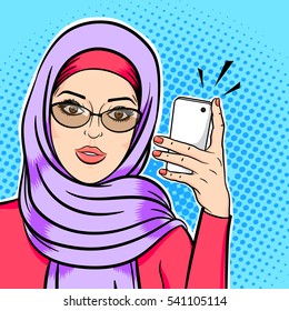 Beautiful modern muslim woman in hijab holding mobile phone reading sms or taking selfie concept vector in pop art comic retro style.