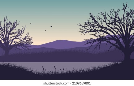 Beautiful mountain view from the riverside at dusk with fantastic silhouettes of the surrounding trees