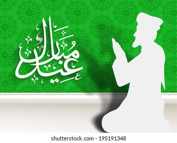 Beautiful paper design of a religious muslim man praying and arabic islamic calligraphy of text Eid Mubarak on green and grey background.  