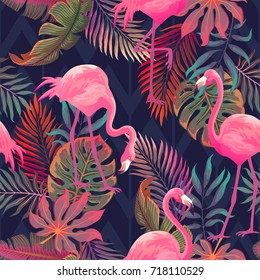 Beautiful seamless vector tropical pattern with pink flamingo and palm leaves on dark background. Abstract summer texture