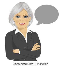 Beautiful senior businesswoman with arms crossed standing next to gray blank speech bubble