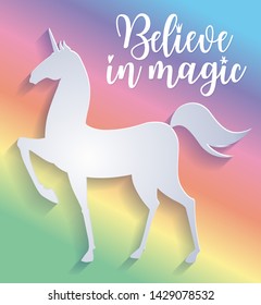 Beautiful silhouette of unicorn in paper cut style. Colorful rainbow background. Typography poster. Believe in magic slogan.