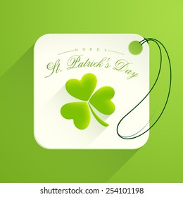 Beautiful tag or label with glossy shamrock leaf on green background for Happy St. Patrick's Day celebration.