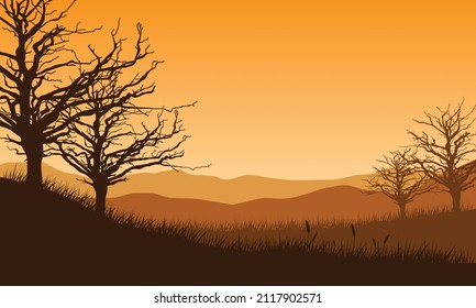 Beautiful view of silhouetted mountains with dry trees from the countryside at sunrise