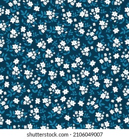 Beautiful vintage pattern. Small white flowers and blue leaves. Dark blue background. Floral seamless background. An elegant template for fashionable prints.