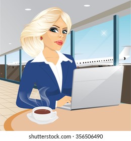 beautiful young blonde businesswoman working at laptop in restaurant and drinking a coffee at airport
