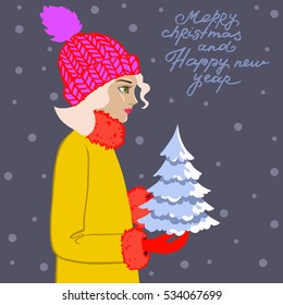 Beautiful young girl in a hat with bubo keeps a small Christmas tree. Merry Christmas and happy new year