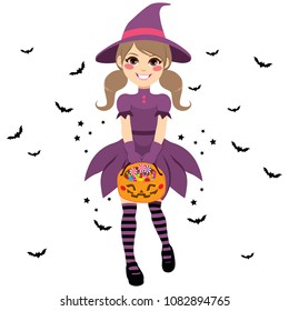 Beautiful young teenager witch wearing purple dress holding trick or treat pumpkin bag