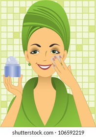beautiful young woman in green bathrobe puts on the face cream