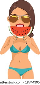 Beautiful young woman wearing bikini and sunglasses eating watermelon