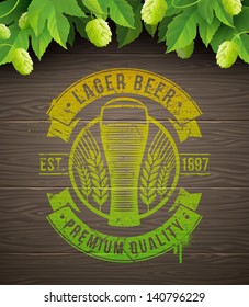 Beer emblem painted on wooden surface and ripe hops and leaves - vector illustration