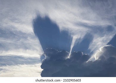 Desde detrás de una nube oscura con bordes plateados, los rayos del sol, que estaban cubiertos por la nube, divergen.