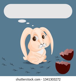 The beige rabbit is looking sadly at a broken chocolate egg and traces of a bird. Egg shell halves. Concept of losing a friend. Place for text.