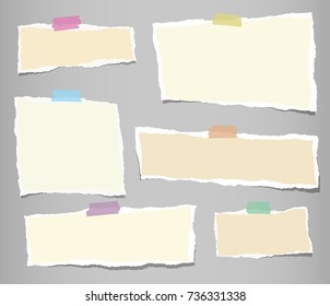 Beige ripped strips, notebook, note paper for text or message stuck with sticky tape on gray background.