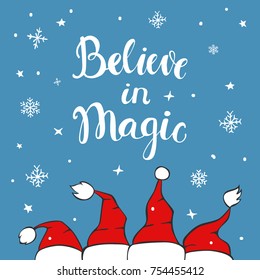 believe in magic xmas background greeting card with chrostmas santa claus hats on blue texture with snowflakes and stars