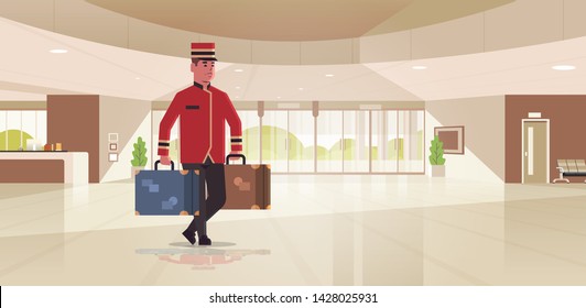 bell boy carrying suitcases hotel service concept bellman holding luggage male worker in uniform modern reception area lobby interior full length horizontal flat