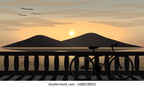 A bicycle is parking on a coast road with sea and an island at sunset.