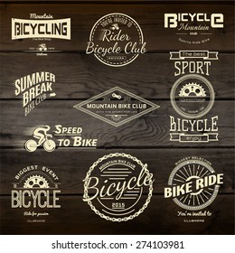 Bicycle set badges logos and labels for any use, on wooden background texture. EPS10