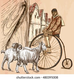 BICYCLIST.Cyclist on the velocipede posing at the old village. In front of old houses are also two goats.Freehand sketching, line drawing. An hand drawn vector illustration.Colored line art technique.