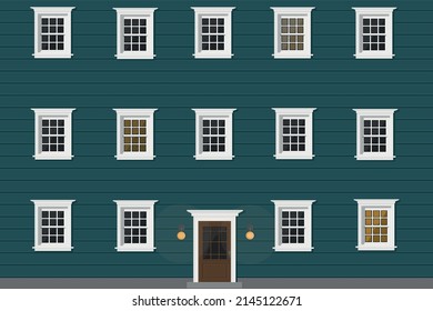 a big blue wooden house with white windows and white door and light in windows in the evening