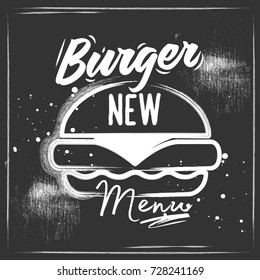 A big chalk black burger with letting on it. Black background