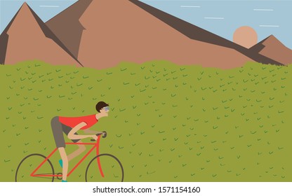bike rider in fields of grass in front of mountains