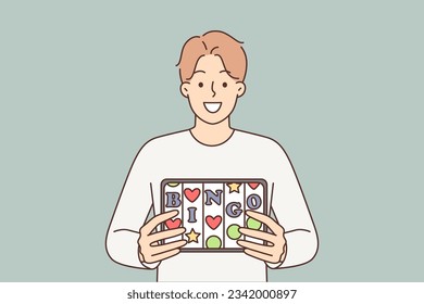 Bingo application in electronic tablet of man offering to visit online casino or try luck in lottery. Guy with smile demonstrates gadget with inscription bingo and slot machine cells