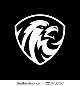 Bird falcon and shield logo design, eagle or hawk badge emblem vector icon on dark background