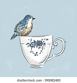 The bird sits on a porcelain cup with blue flowers.