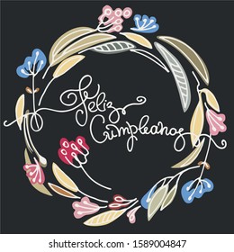 Birthday greeting in Spanish. Text says Happy Birthday. Floral wreath and hand lettering on black backgound