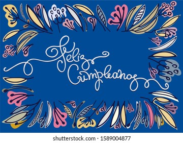 Birthday greeting in Spanish. Text says Happy Birthday. Floral frame and hand lettering isolated on blue backgound