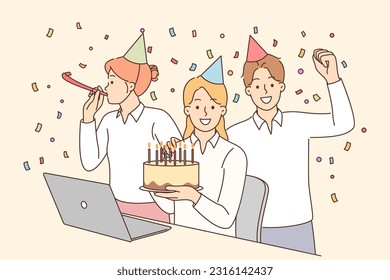 Birthday party with office colleagues and friends from work giving cake and using confetti. Happy girl sits at table with laptop near business partners who congratulated on birthday