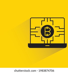 bitcoin on laptop with shadow on yellow background