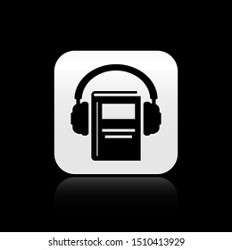 Black Audio book icon isolated on black background. Book with headphones. Audio guide sign. Online learning concept. Silver square button. Vector Illustration