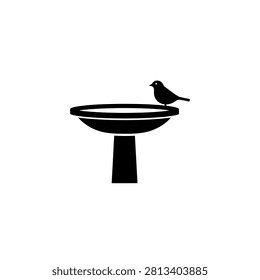 A black bird sitting on birdbath