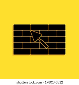 Black Brick wall with trowel icon isolated on yellow background. Long shadow style. Vector