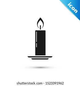 Black Burning candle in candlestick icon isolated on white background. Old fashioned lit candle. Cylindrical candle stick with burning flame.  Vector Illustration