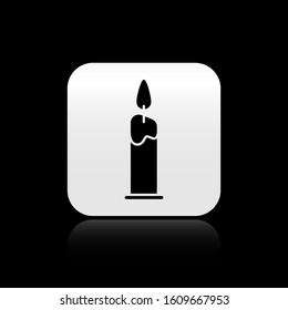 Black Burning candle in candlestick icon isolated on black background. Cylindrical candle stick with burning flame. Silver square button. Vector Illustration