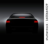 Black car with back red lights on dark background.